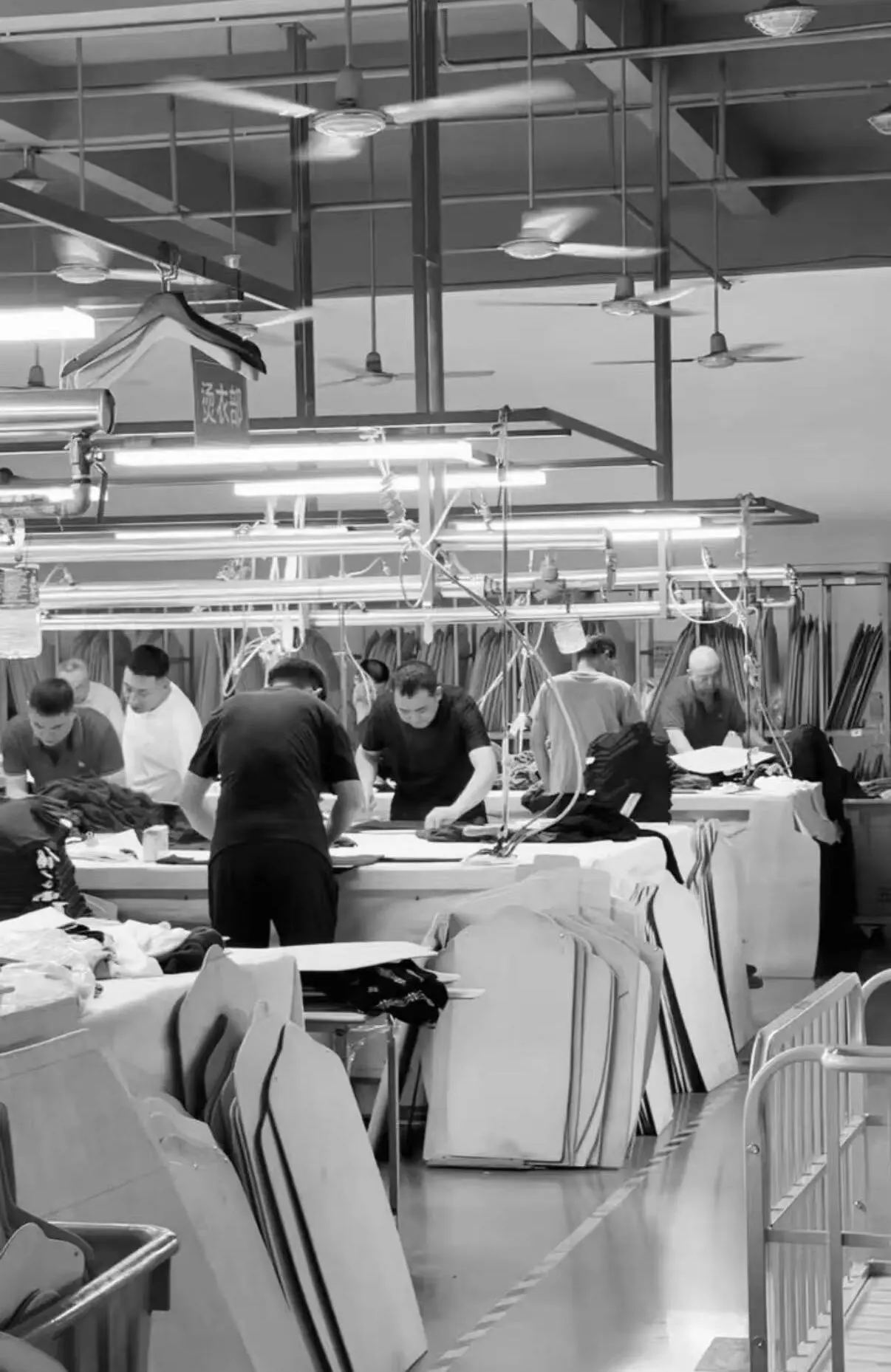 EtrenerKnit factory production floor — workers handling knitwear at long tables under industrial lighting